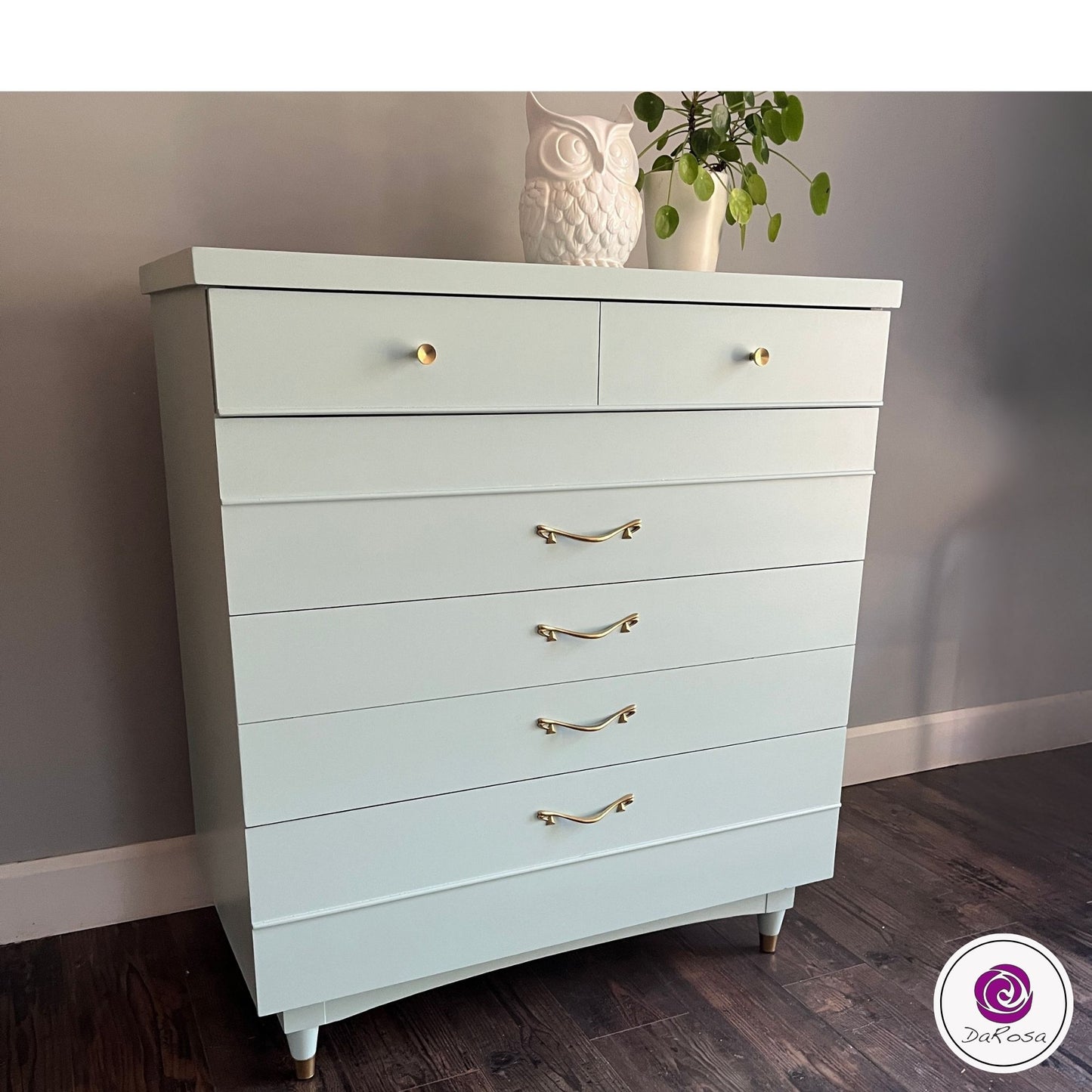 Light blue dresser with gold handles against a gray wall.